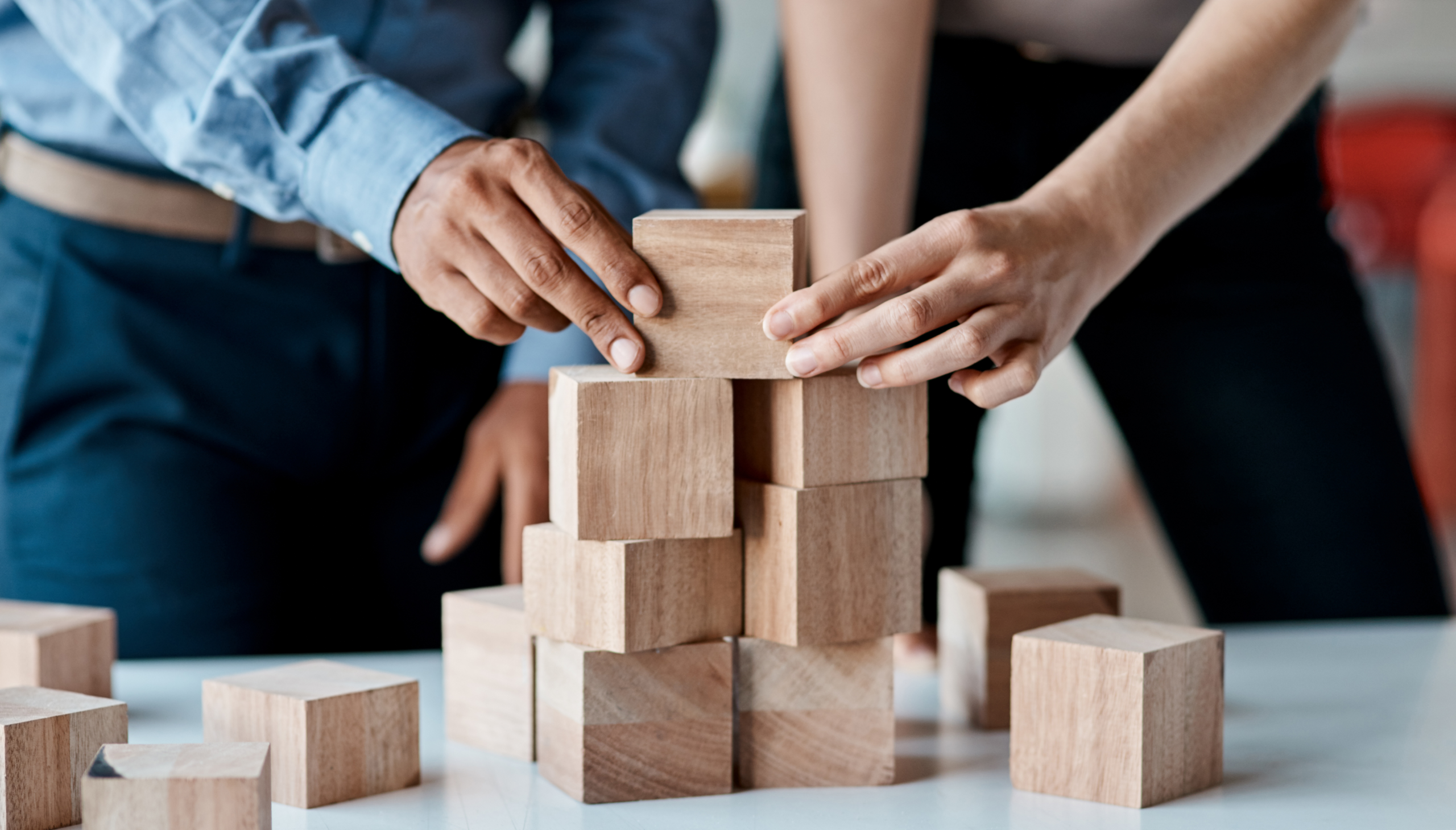 Hands stacking wooden blocks on table.