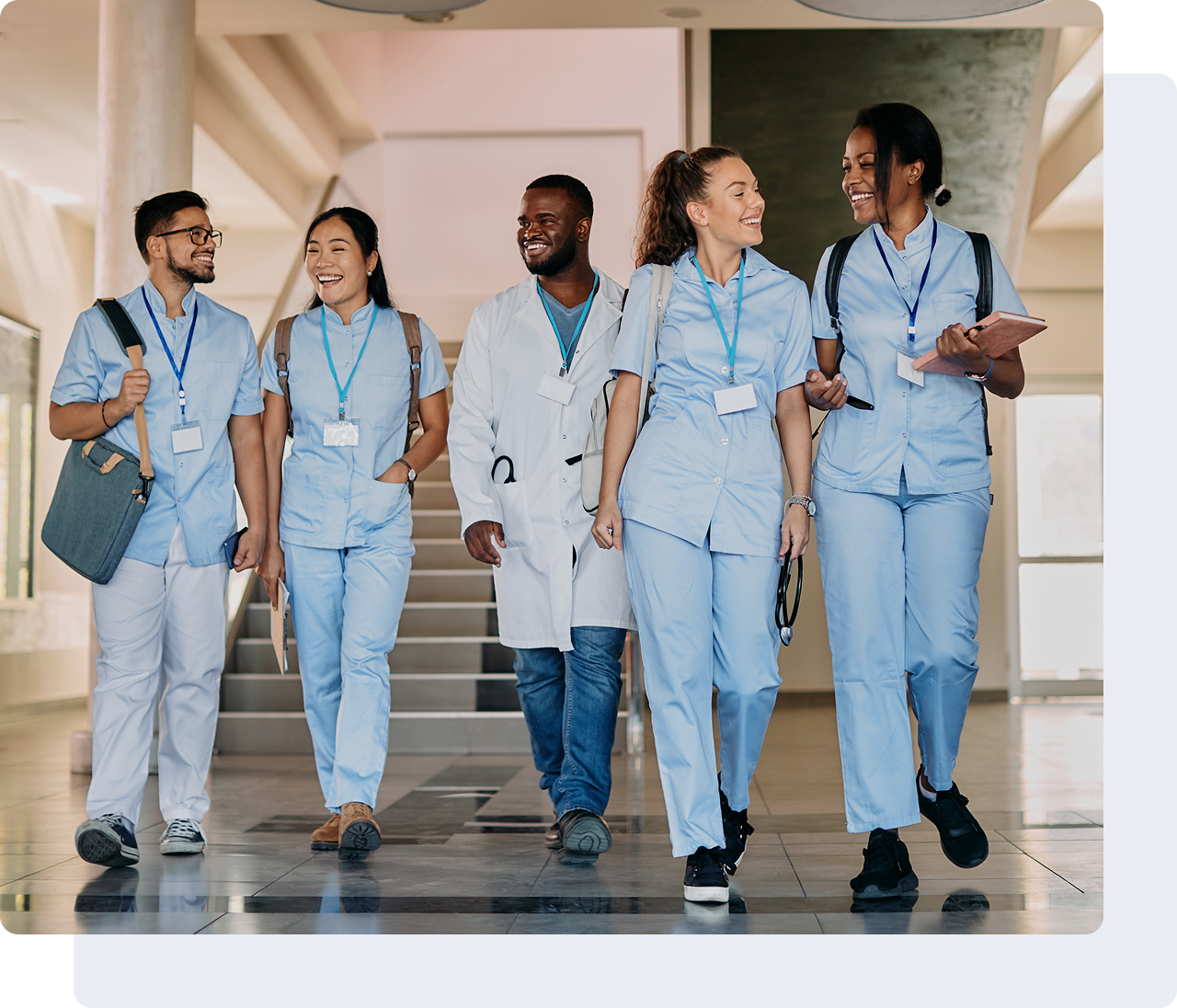 Medical team walking down hospital corridor smiling.
