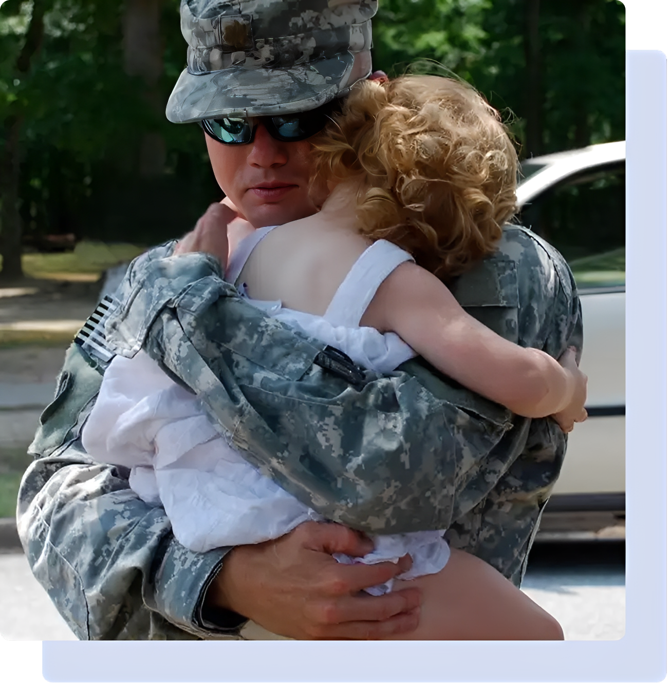 Soldier embracing child in outdoor setting.