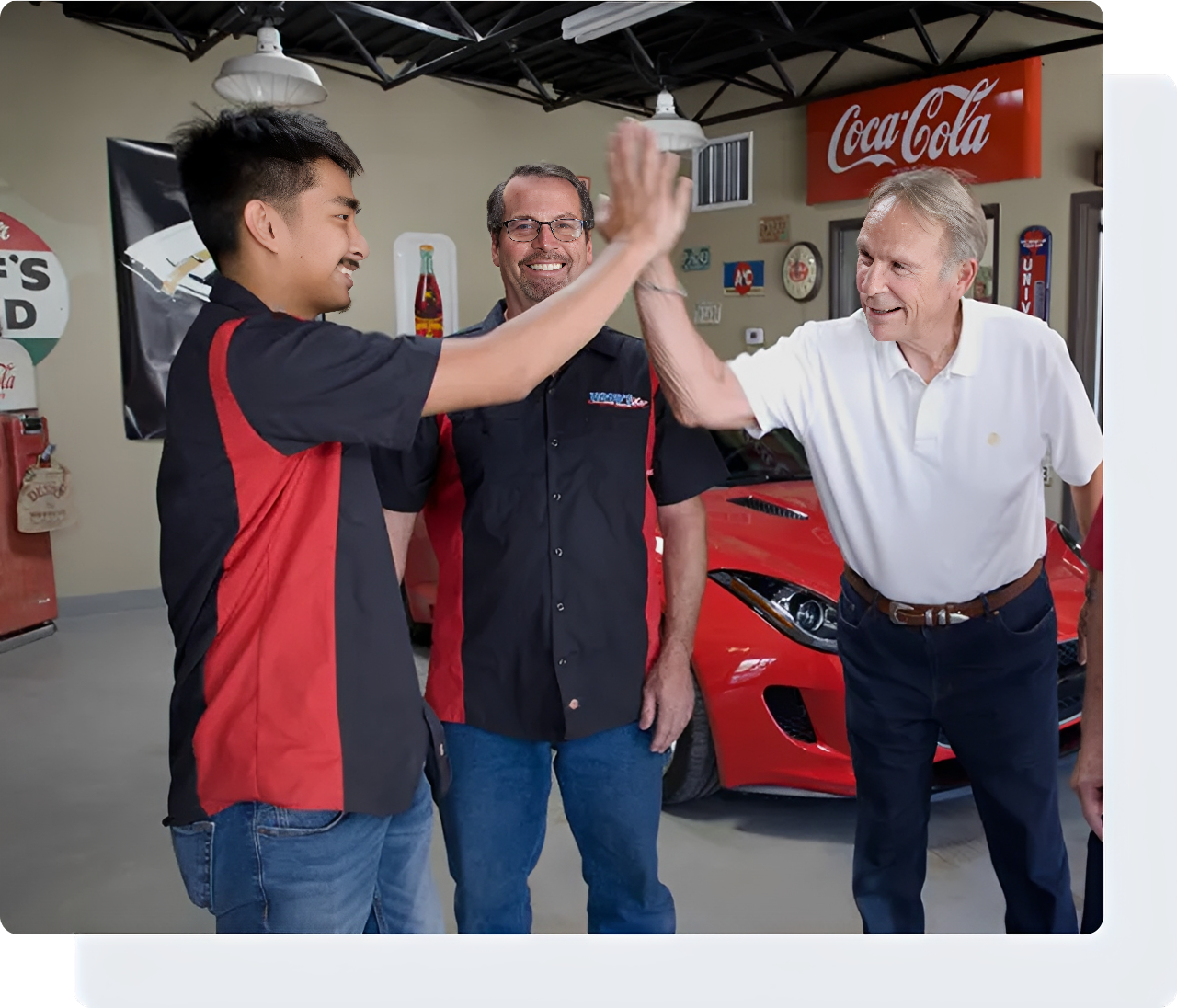 Three men high-fiving in a garage.
