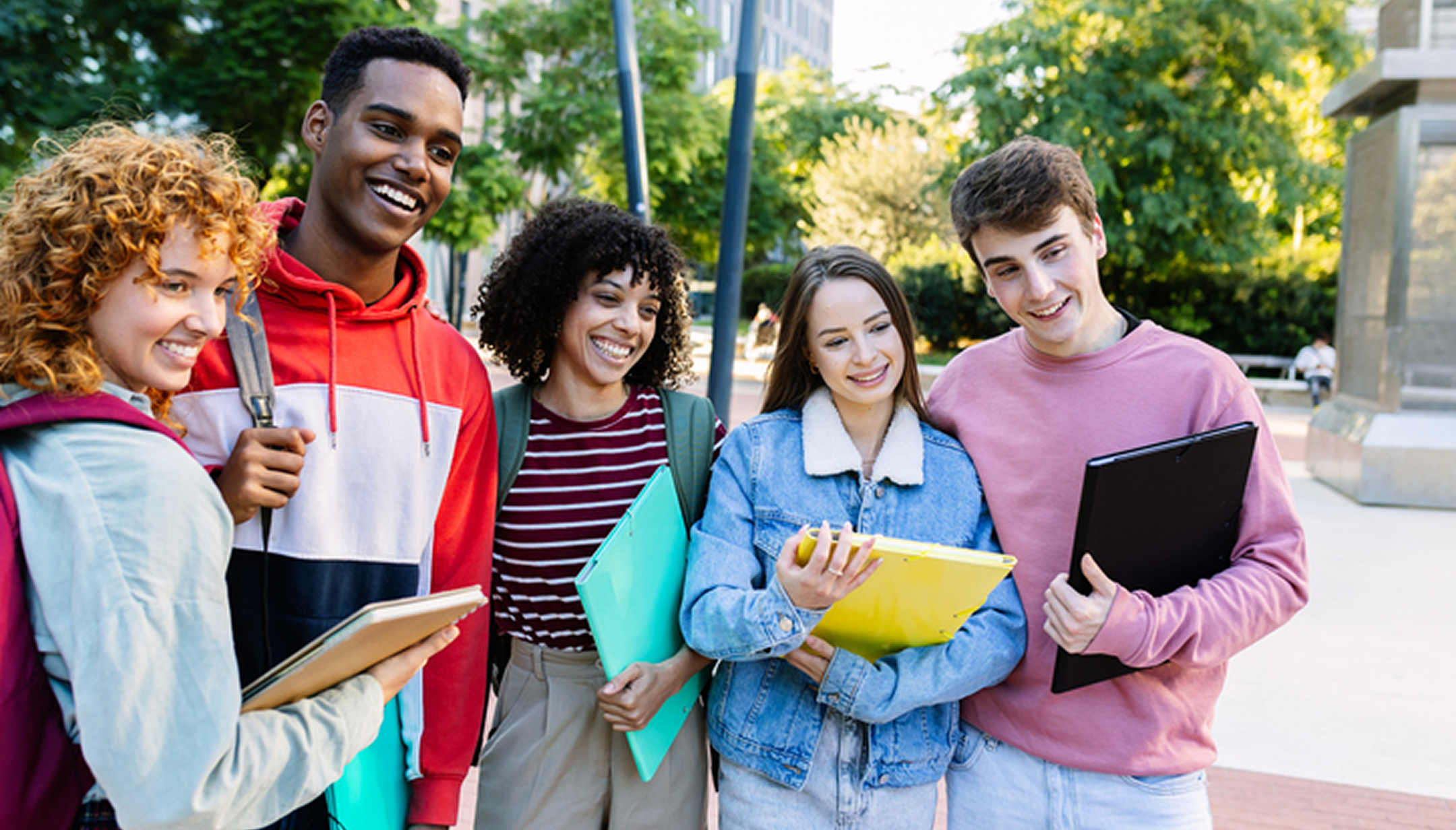 Group of students smiling with notebooks outside.