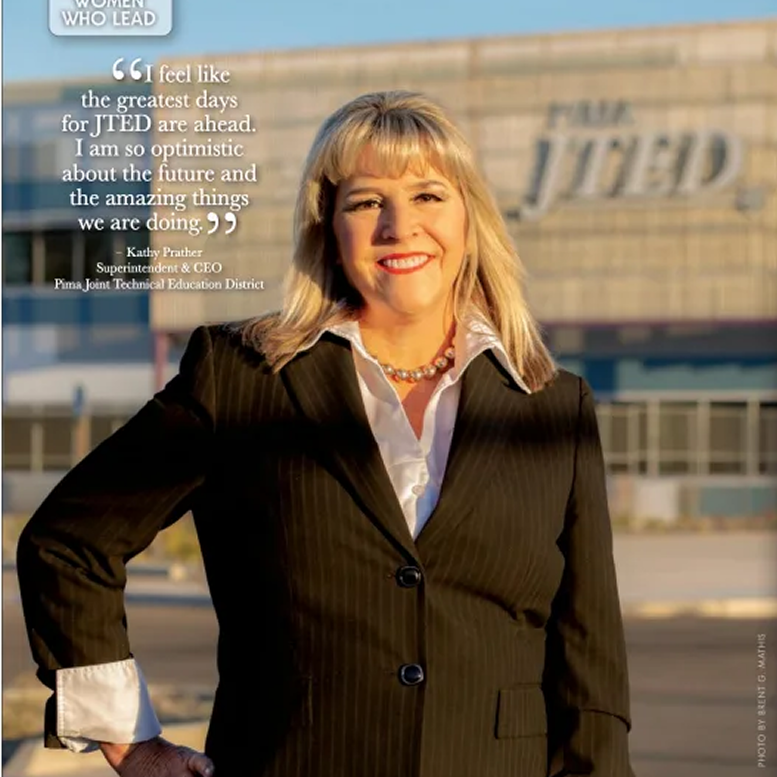 Woman in business attire standing outside building.