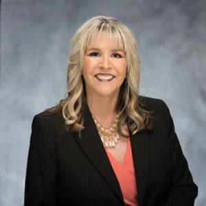 Smiling woman in business attire, gray background.